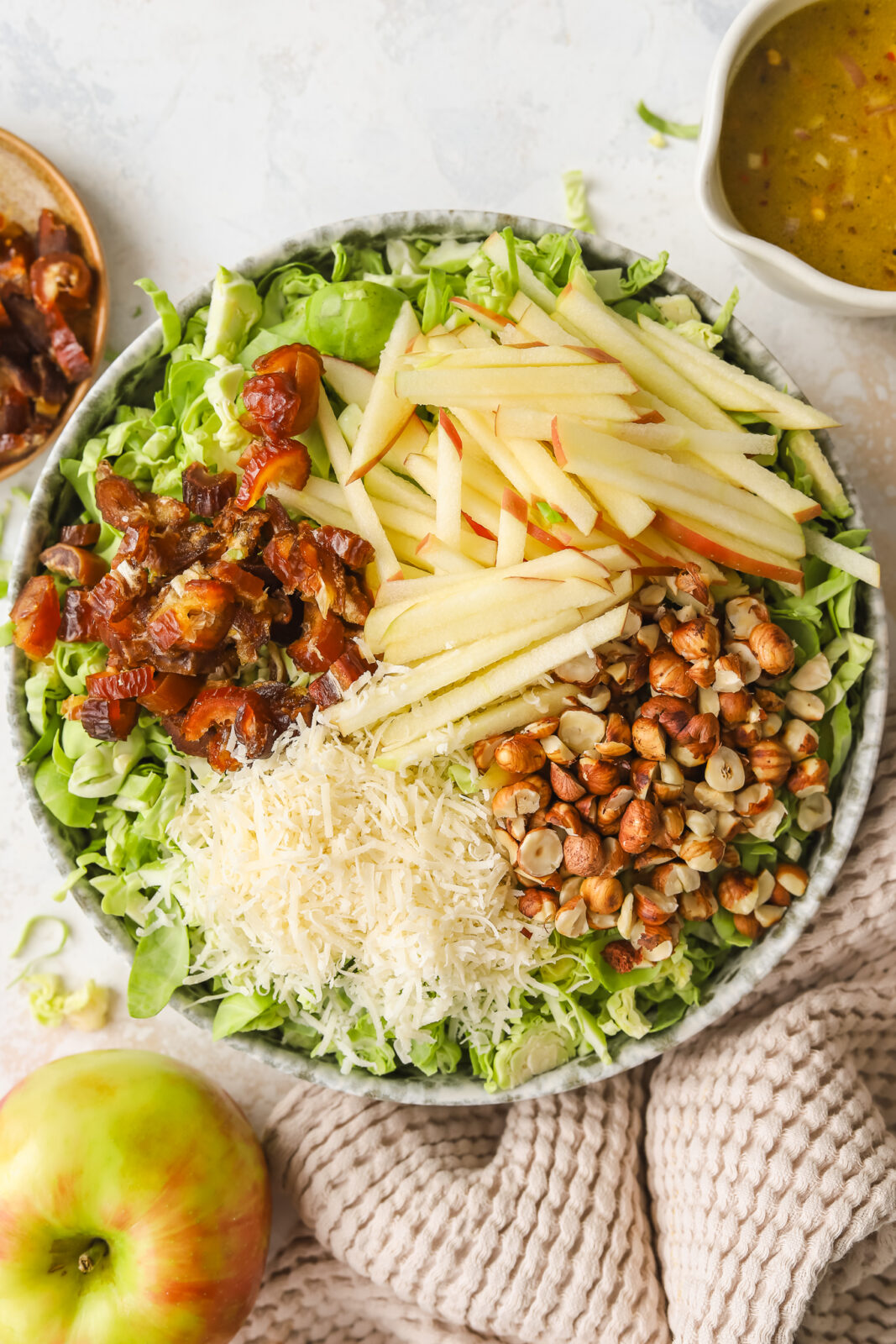 chopped dates, sliced apples, parmesan cheese and toasted hazelnuts in a bowl with brussels sprouts