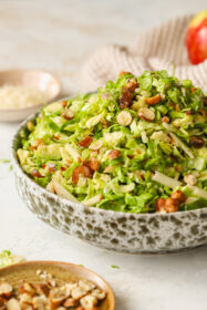 side angle of brussels sprouts salad in a bowl with hazelnuts, dates and apples