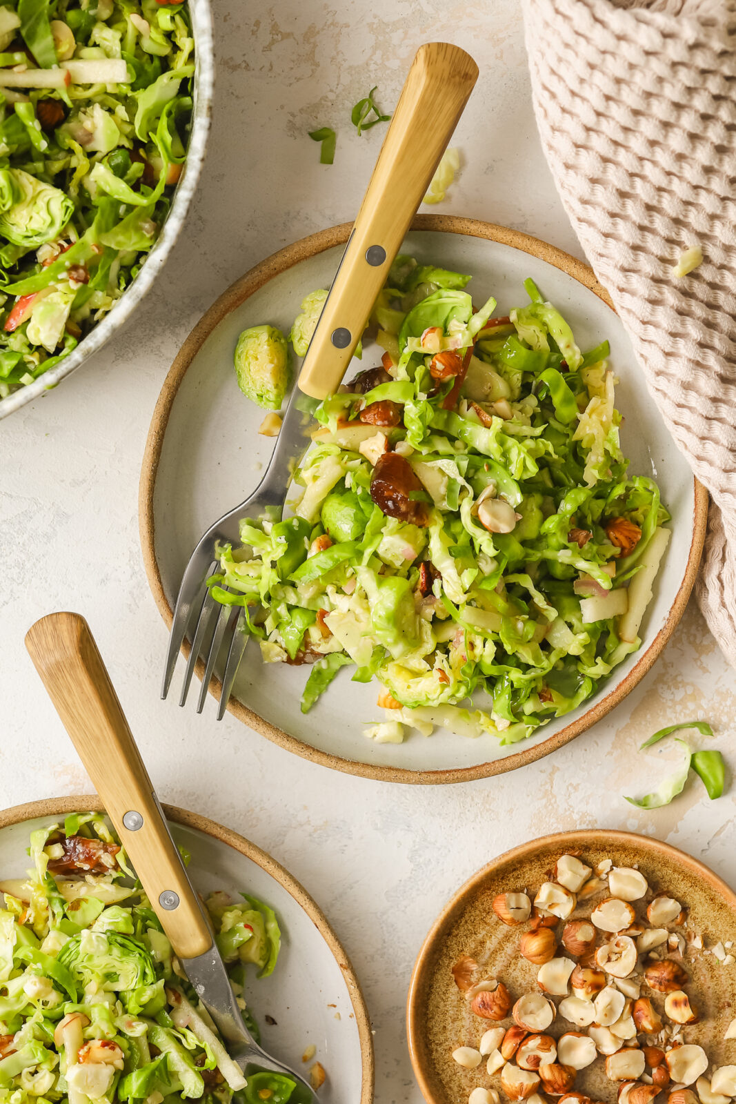 brussels sprouts salad on side plates with hazelnuts, dates and apples
