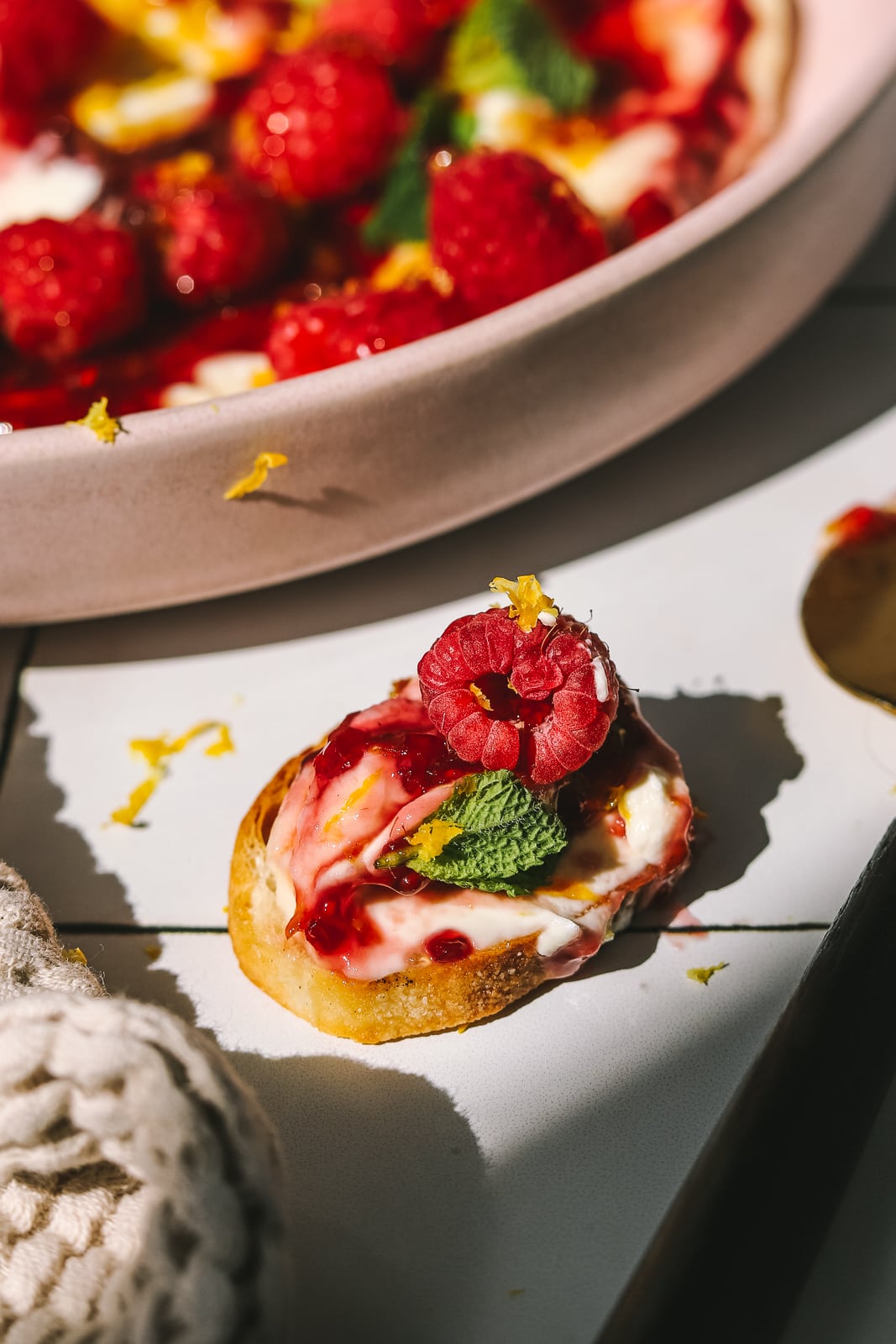 crostini topped with cream cheese dip, raspberries and lemon