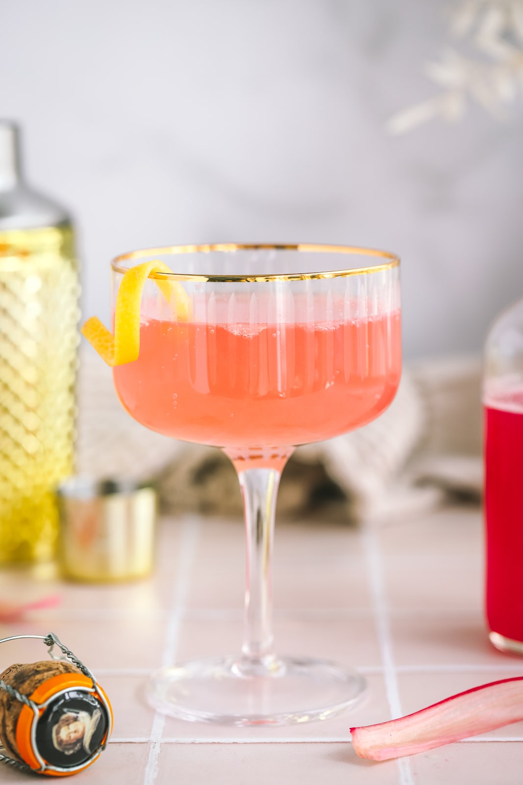 a rhubarb french 75 in a coupe glass with a lemon twist