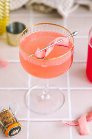 a rhubarb french 75 in a coupe glass with a rhubarb garnish