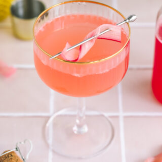 a rhubarb french 75 in a coupe glass with a rhubarb garnish