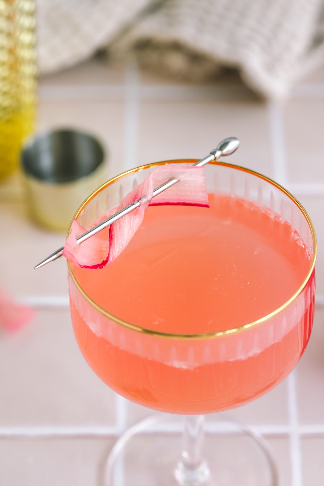 a rhubarb french 75 in a coupe glass with a rhubarb garnish