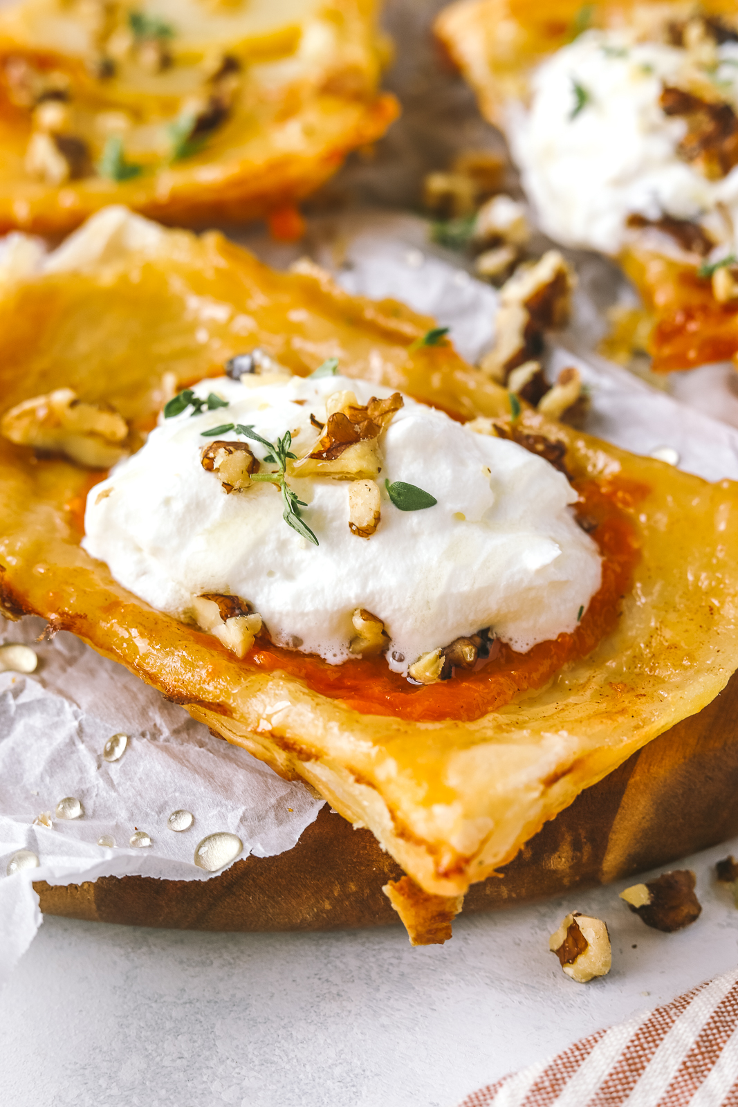 upside down apricot puff pastry tart topped with whipped cream, walnuts and thyme