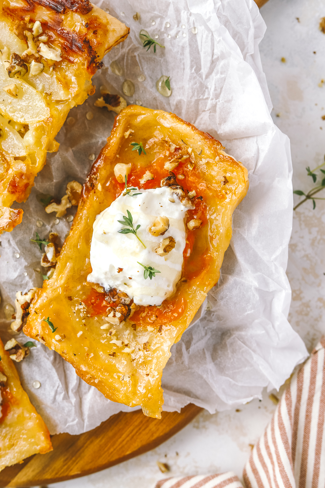 upside down apricot puff pastry tart topped with whipped cream, walnuts and thyme