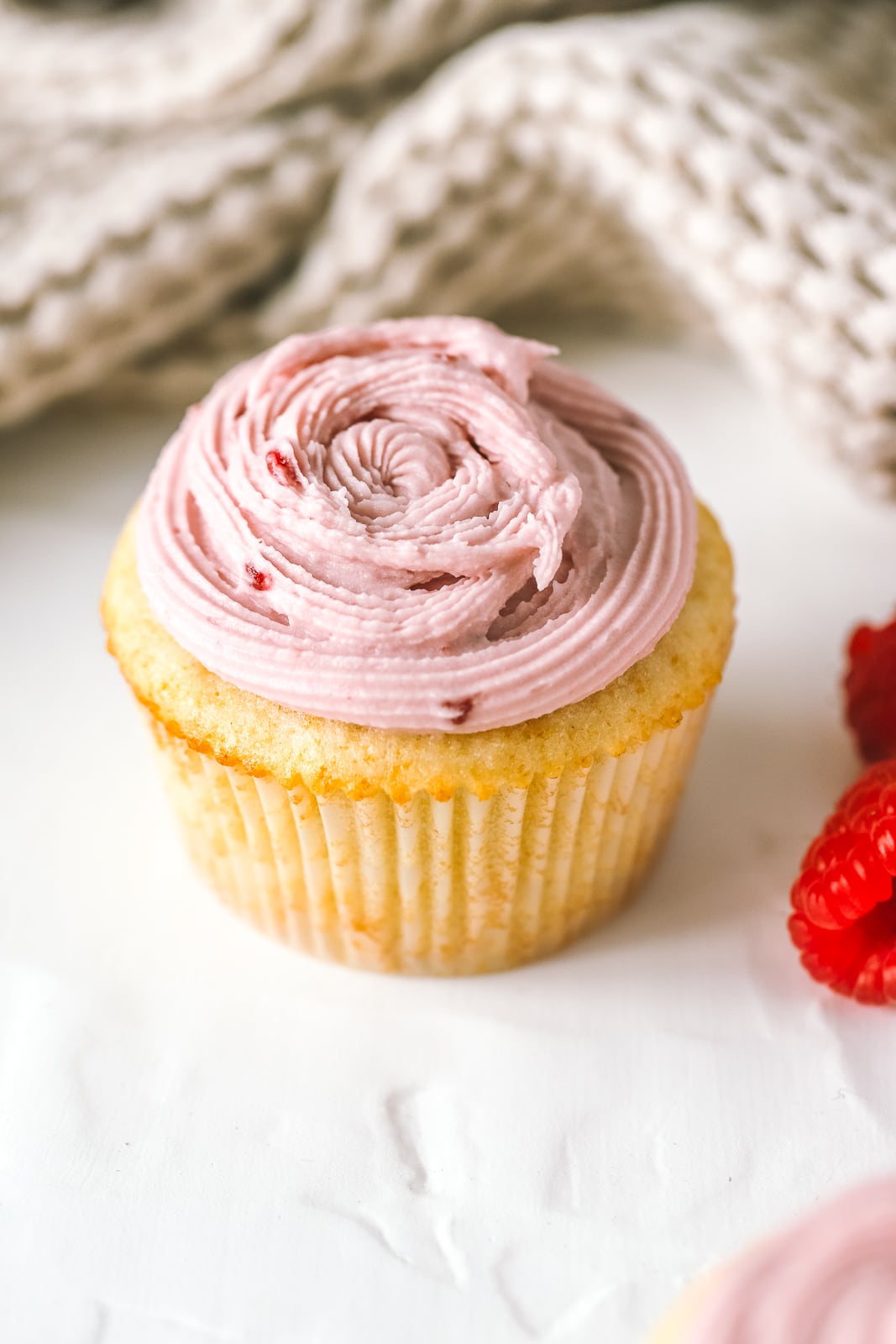 vanilla cupcake topped with raspberry cream cheese frosting