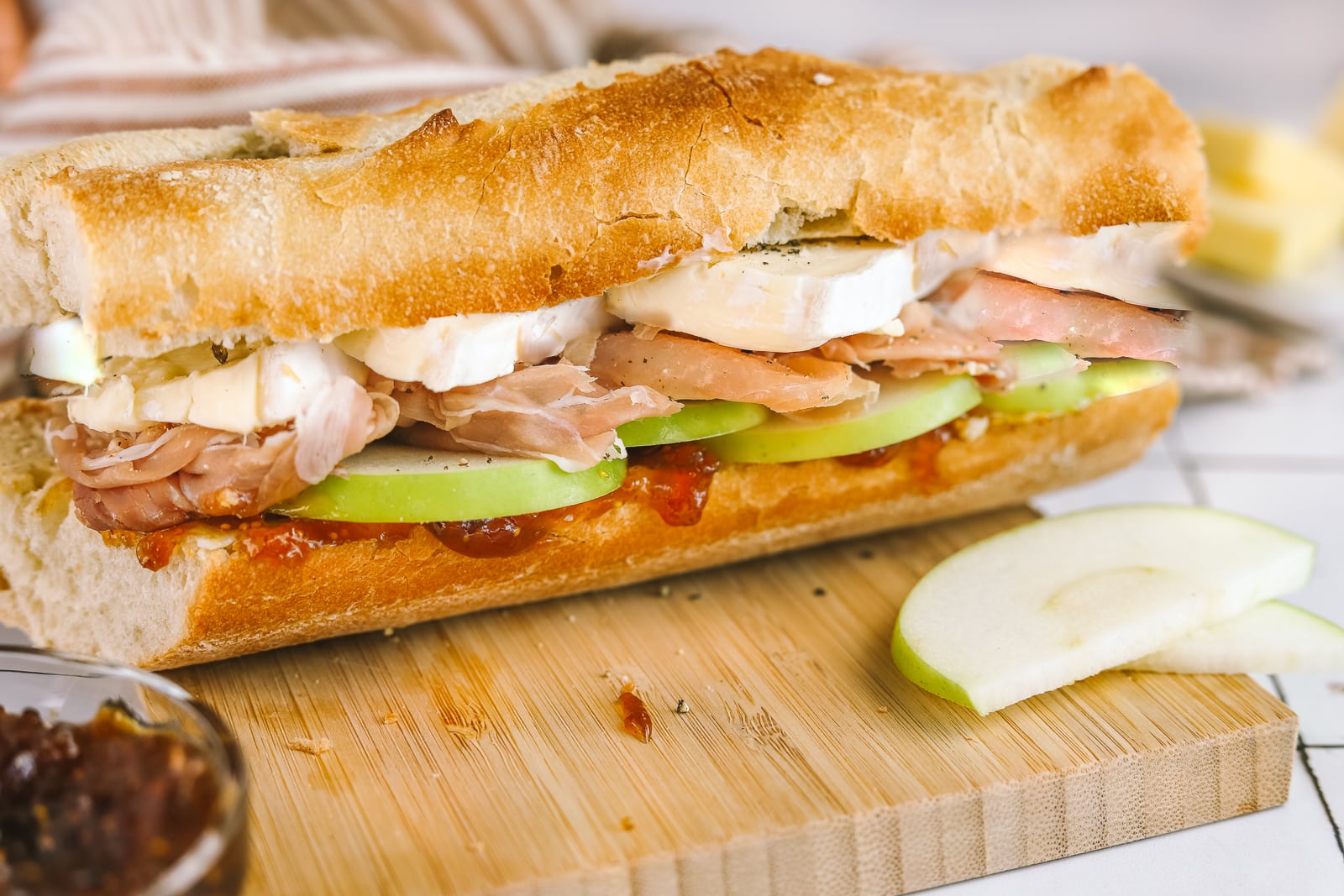 closeup of brie sandwich with prosciutto, apples and fig jam