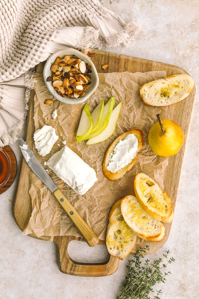 Pear, goat cheese, crostini, almonds on a cheeseboard