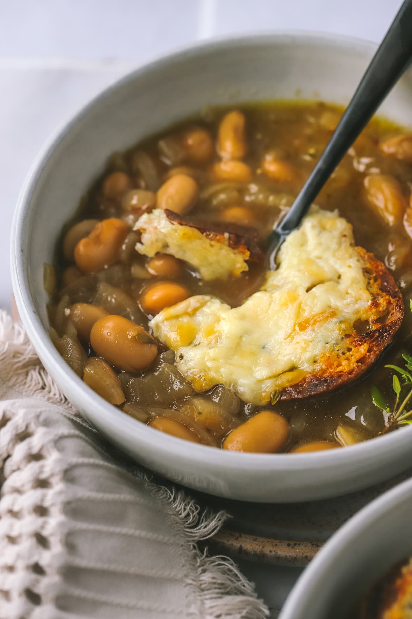 side view of french onion bean soup with spoon