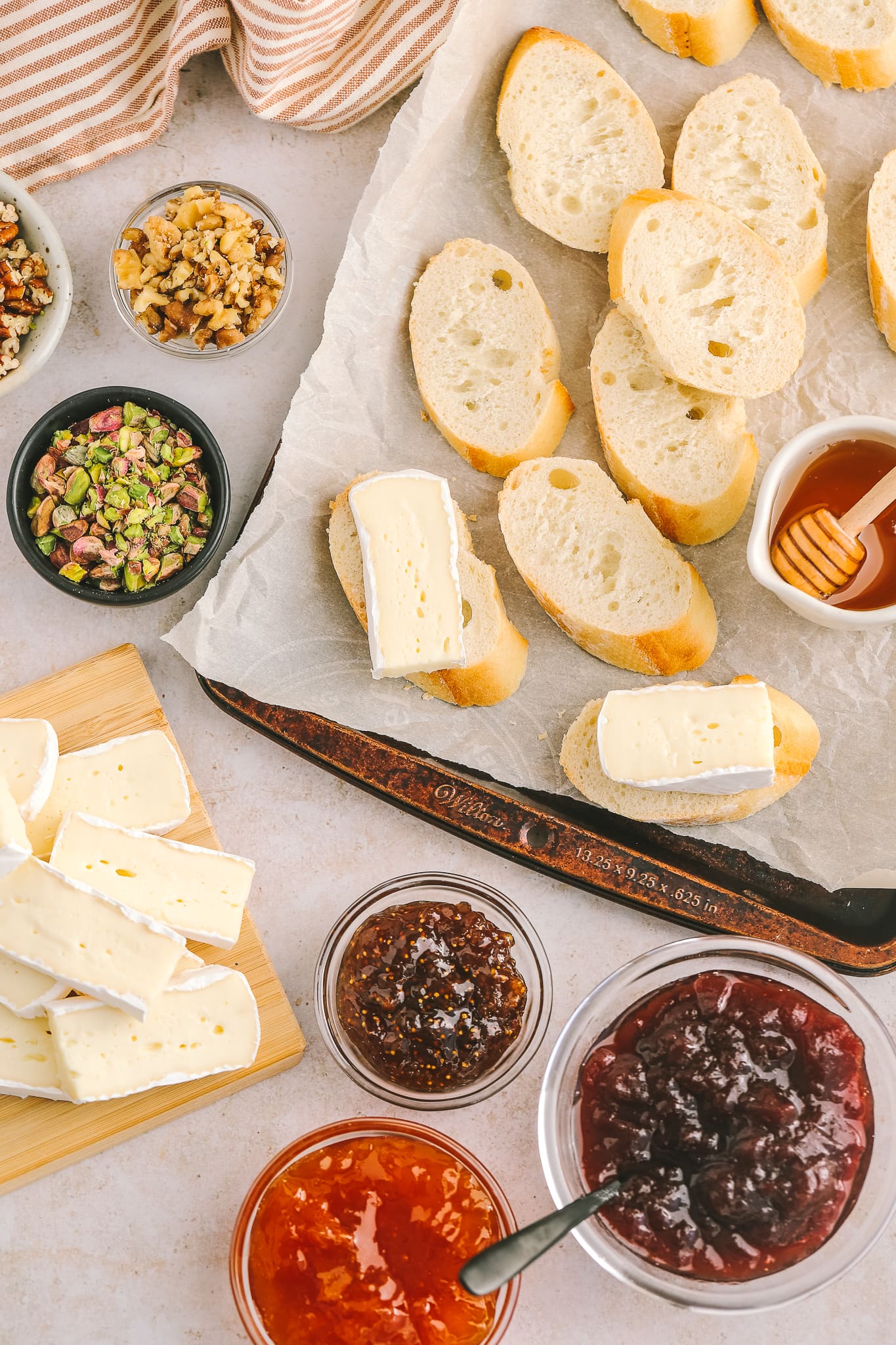 ingredients to make appetizers: brie cheese, baguette, jams and nuts