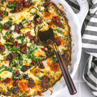 cheesy baked pesto dip with a serving knife