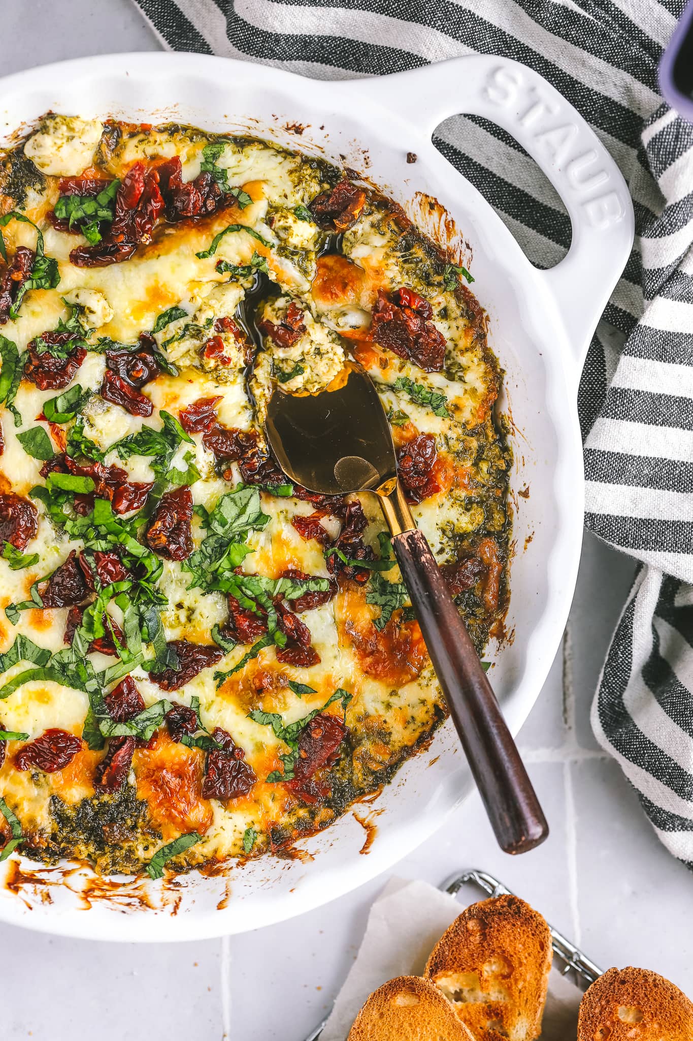 cheesy baked pesto dip with a serving knife