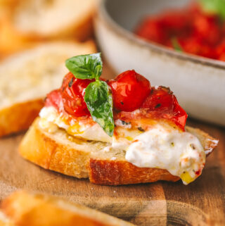 side angle of burrata on bread topped with roasted tomatoes