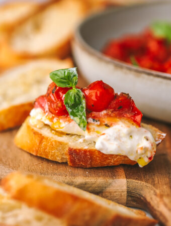 side angle of burrata on bread topped with roasted tomatoes