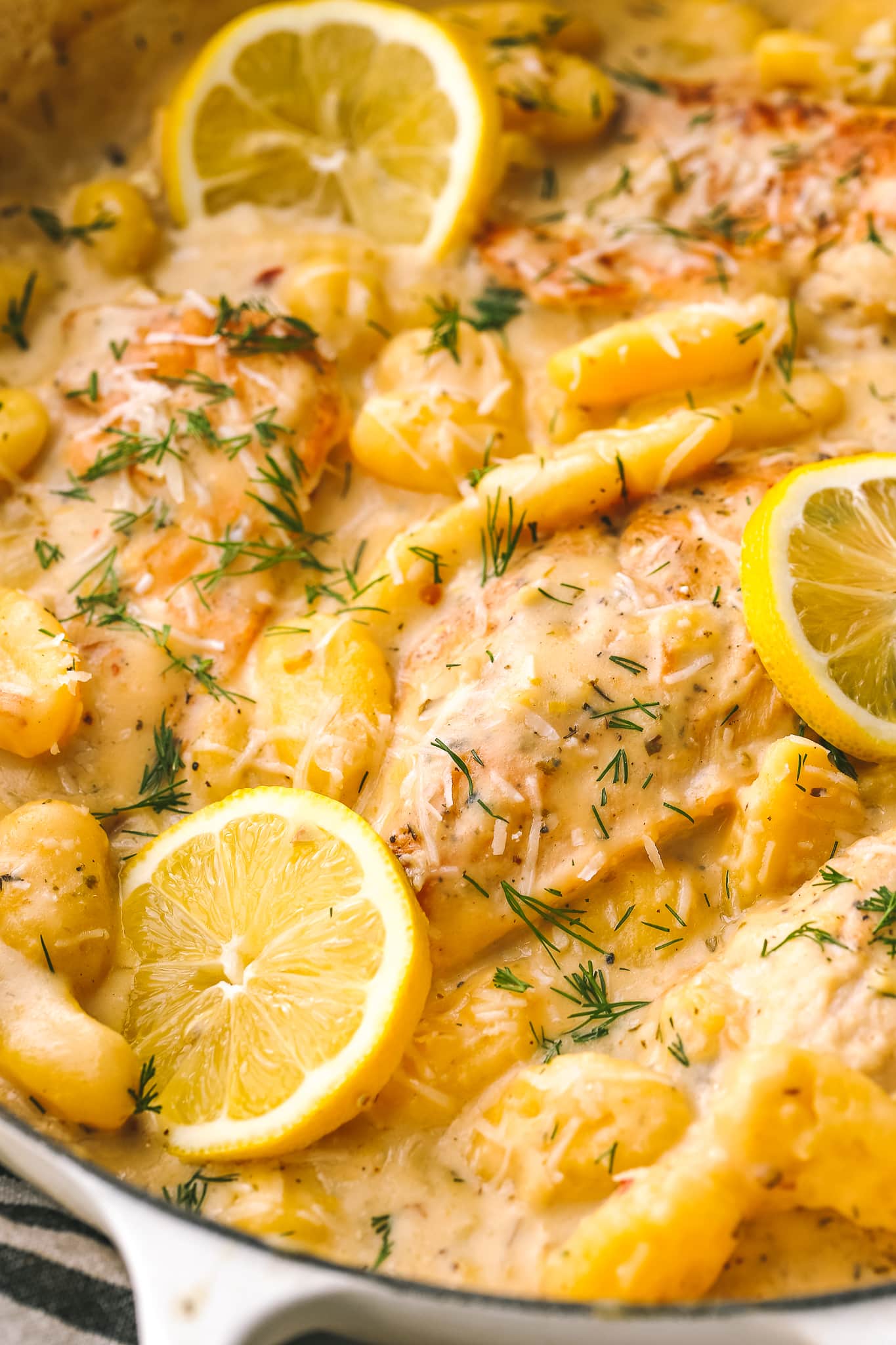 closeup of cooked chicken, gnocchi and lemon in a large pan