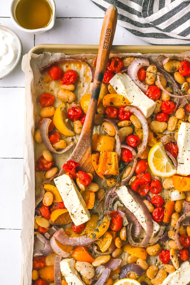 overhead photo of sheet pan dinner with feta with a serving spoon