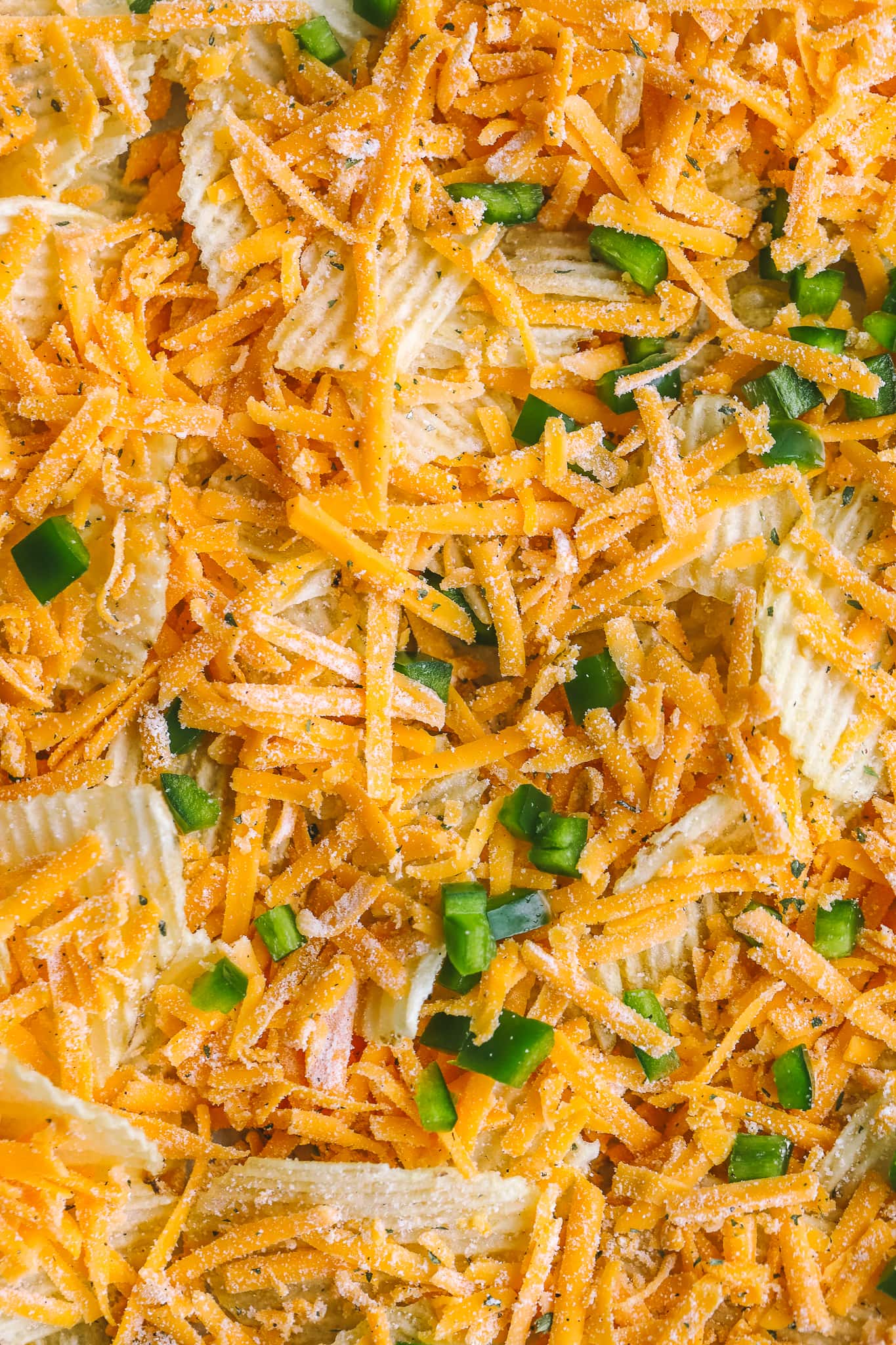 close up of shredded cheese and jalapenos on wavy chips