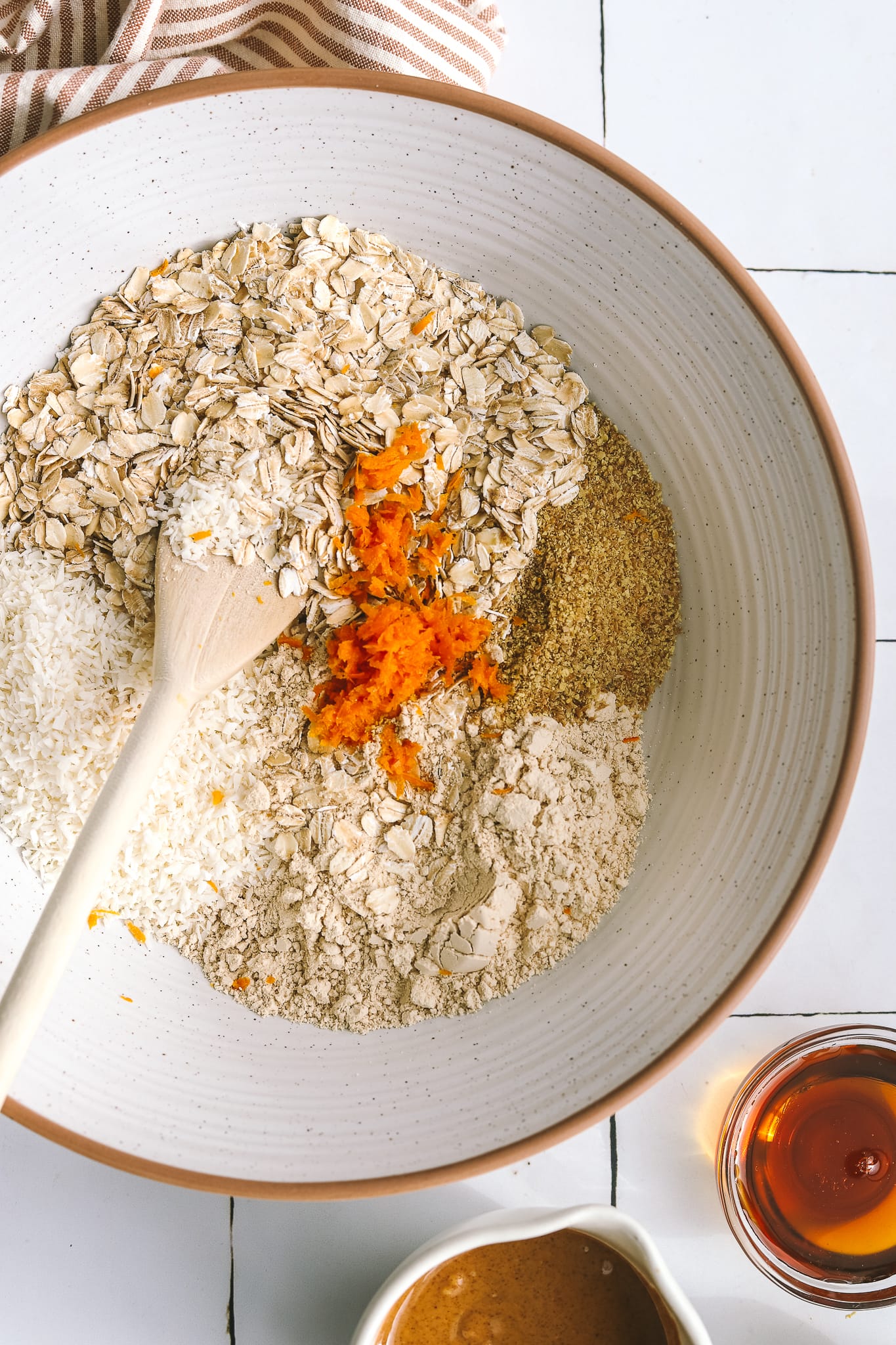 close up of coconut, oats, citrus, protein powder and flaxseed in a mixing bowl