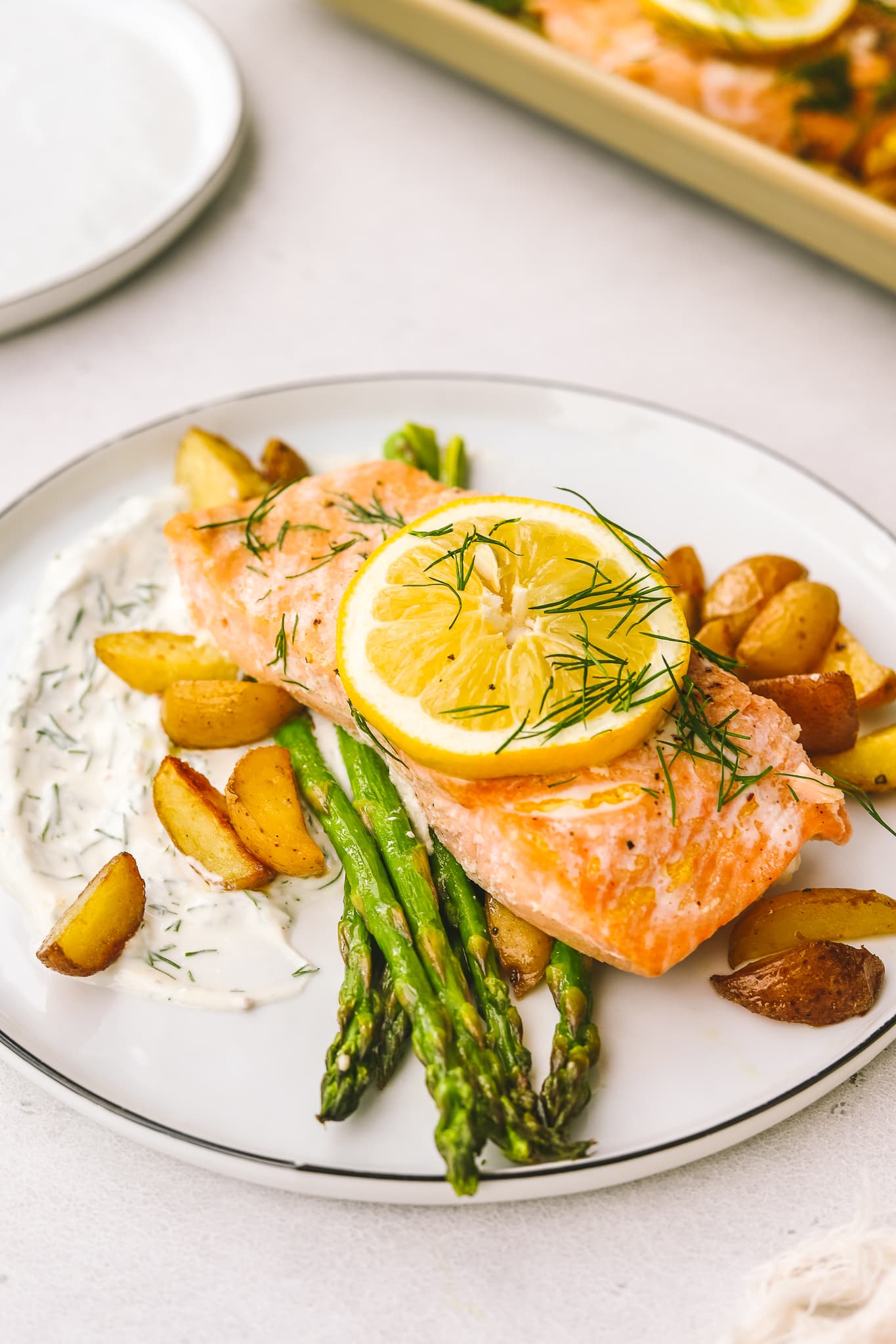 salmon on a plate with asparagus, potatoes and dill sauce