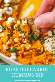 hand holding cracker dipping in roasted carrot hummus