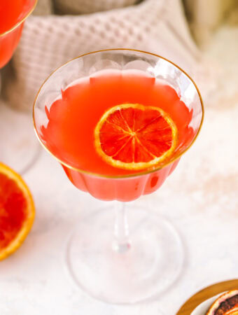 angled shot of a glass with blood orange martini and blood orange garnish