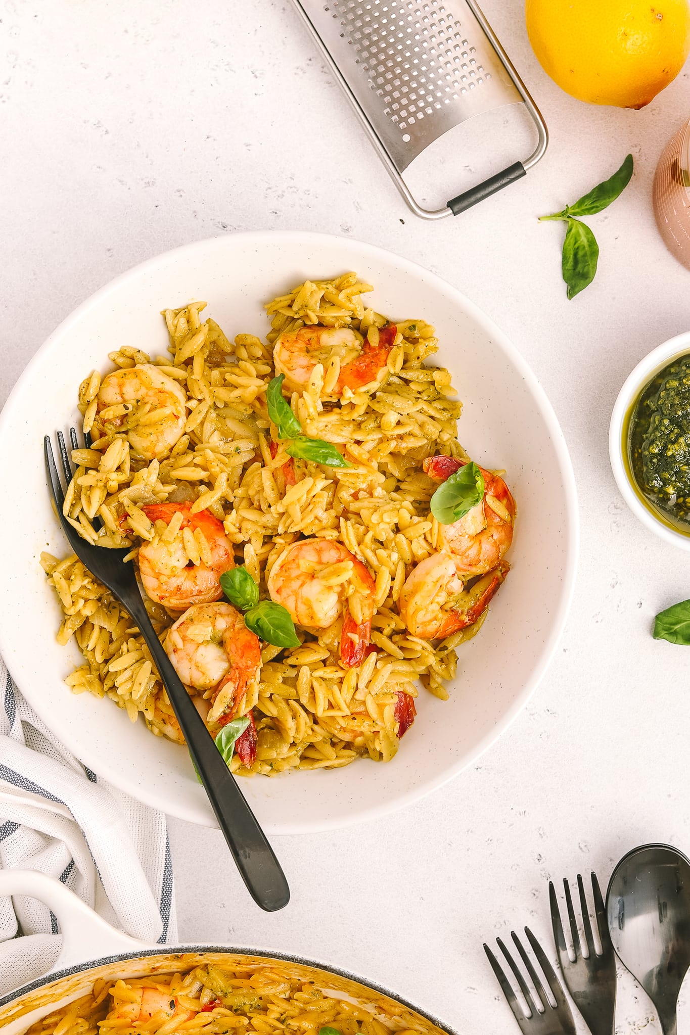 white bowl with orzo, cooked shrimp and side of pesto