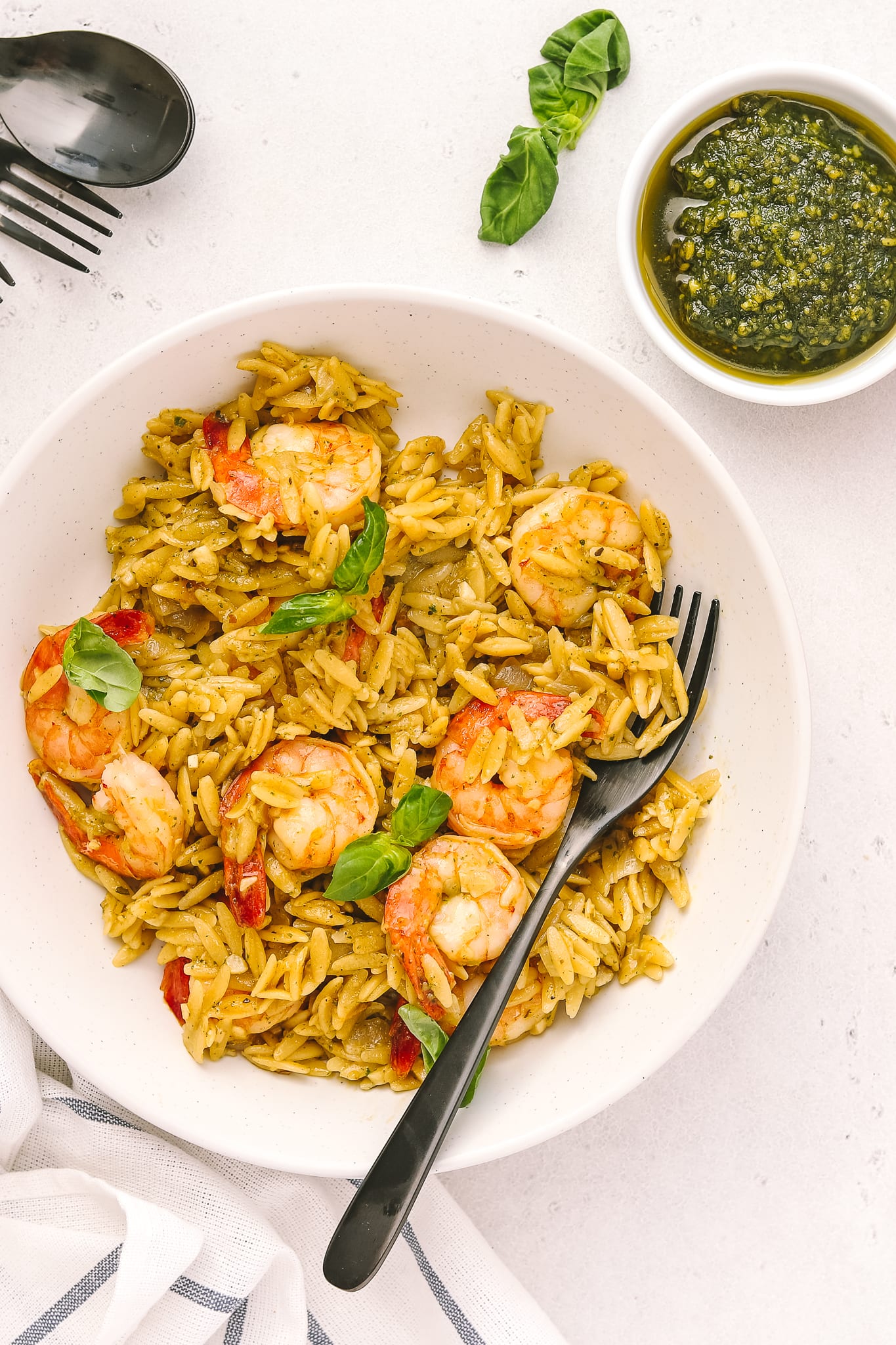 white bowl with orzo, cooked shrimp and side of pesto