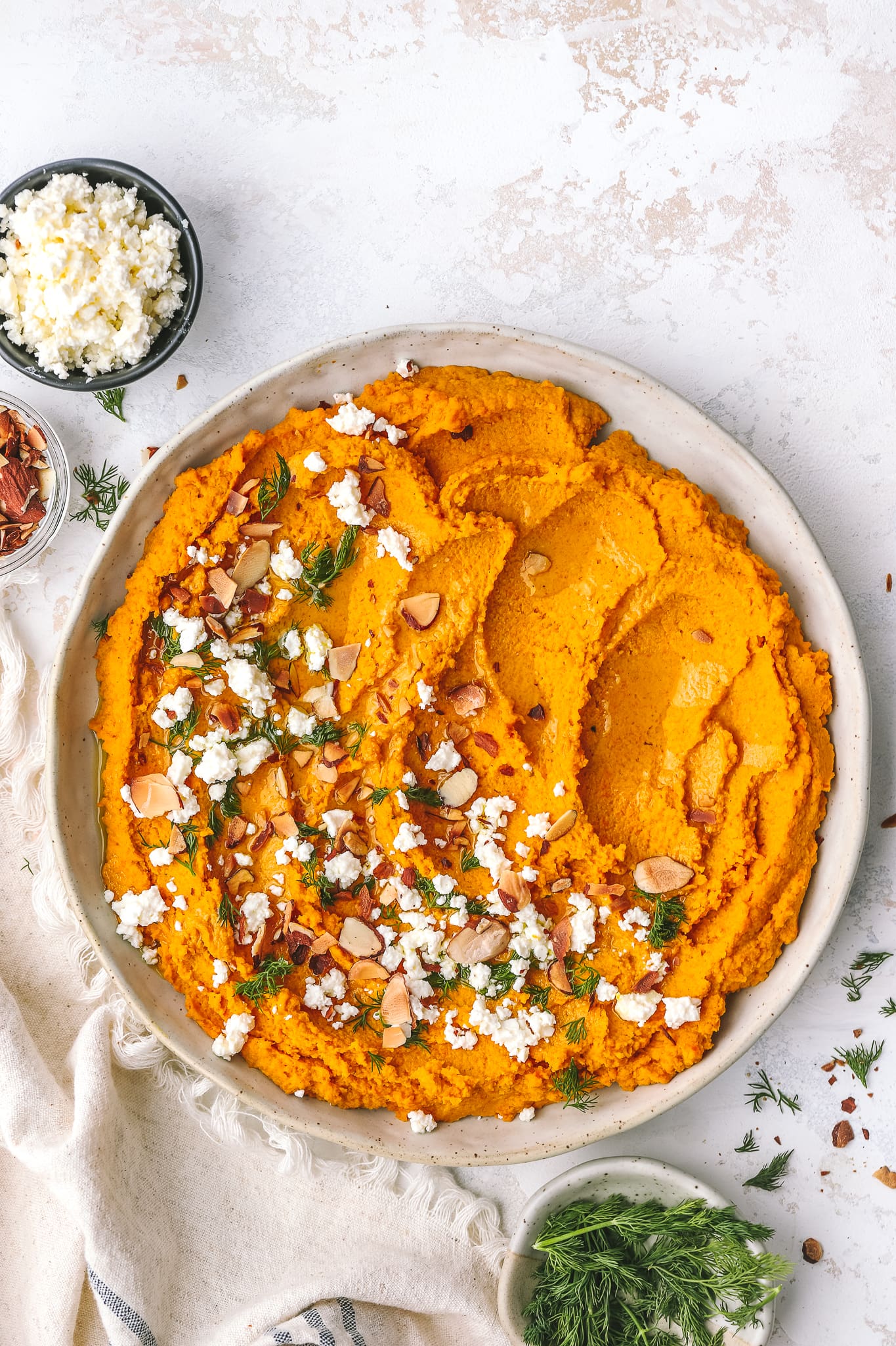 carrot hummus spread in a low bowl with toppings