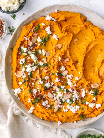 carrot hummus spread in a low bowl with toppings