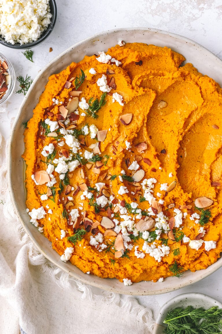 carrot hummus spread in a low bowl with toppings