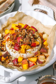 10 Recipes for Brie Cheese With Flavors For Every Season angled shot of peach baked brie in a baking dish