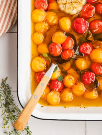 spoon in a baking dish of tomatoes and oil