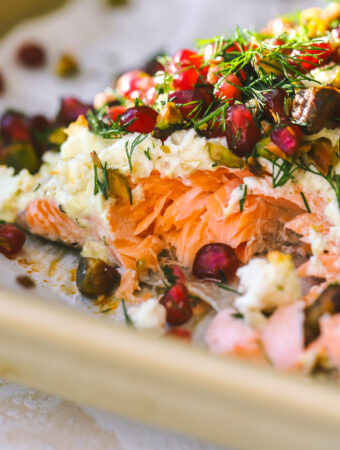 close up of baked salmon with pomegranate seeds, dill and pistachios