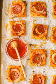 hot honey in a bowl with pepperoni pizza tarts on a tray
