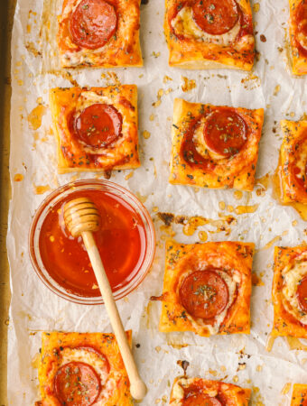 hot honey in a bowl with pepperoni pizza tarts on a tray