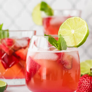 berry rhubarb kombucha sangria in a glass garnished with lime and fresh mint