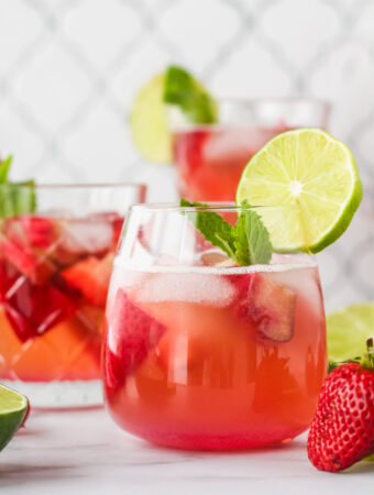 berry rhubarb kombucha sangria in a glass garnished with lime and fresh mint