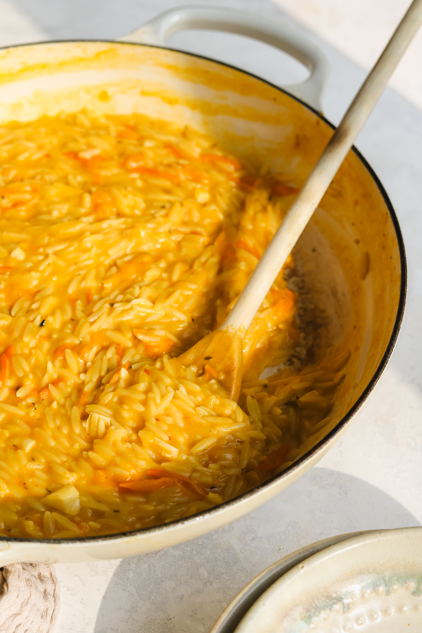 close up of wooden spoon in cooked tomato orzo