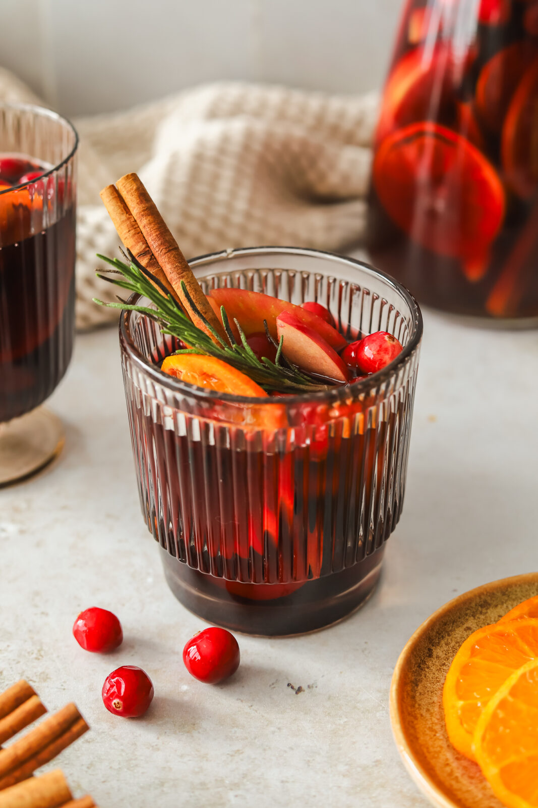 glass of red sangria with oranges, apples, cinnamon stick and rosemary
