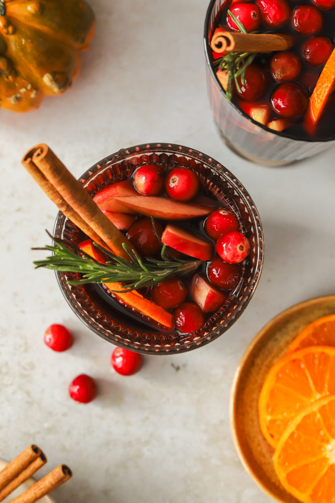 glass of red sangria with oranges, apples, cinnamon stick and rosemary