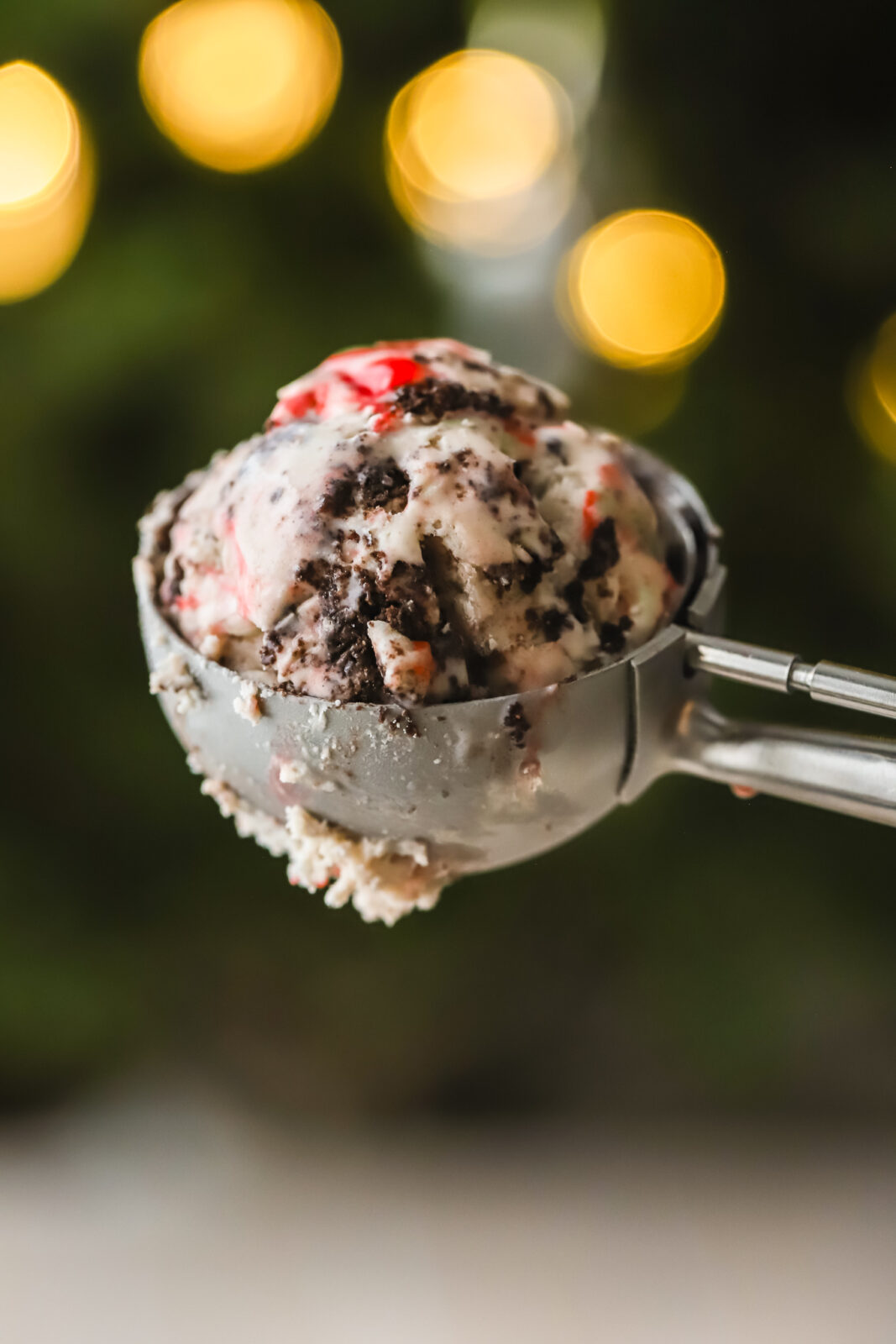 peppermint Oreo ice cream in a scoop in front of a Christmas tree