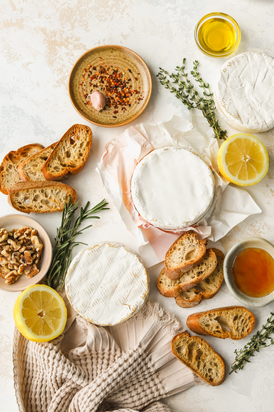 wheels of camembert cheese, lemon slices, olive oil, hot honey, walnuts and crostini