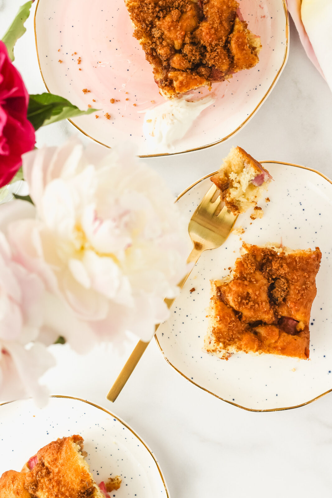 rhubarb cake on a plate with flowers nearby