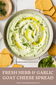 herby goat cheese spread in a shallow bowl with crackers and fresh herbs