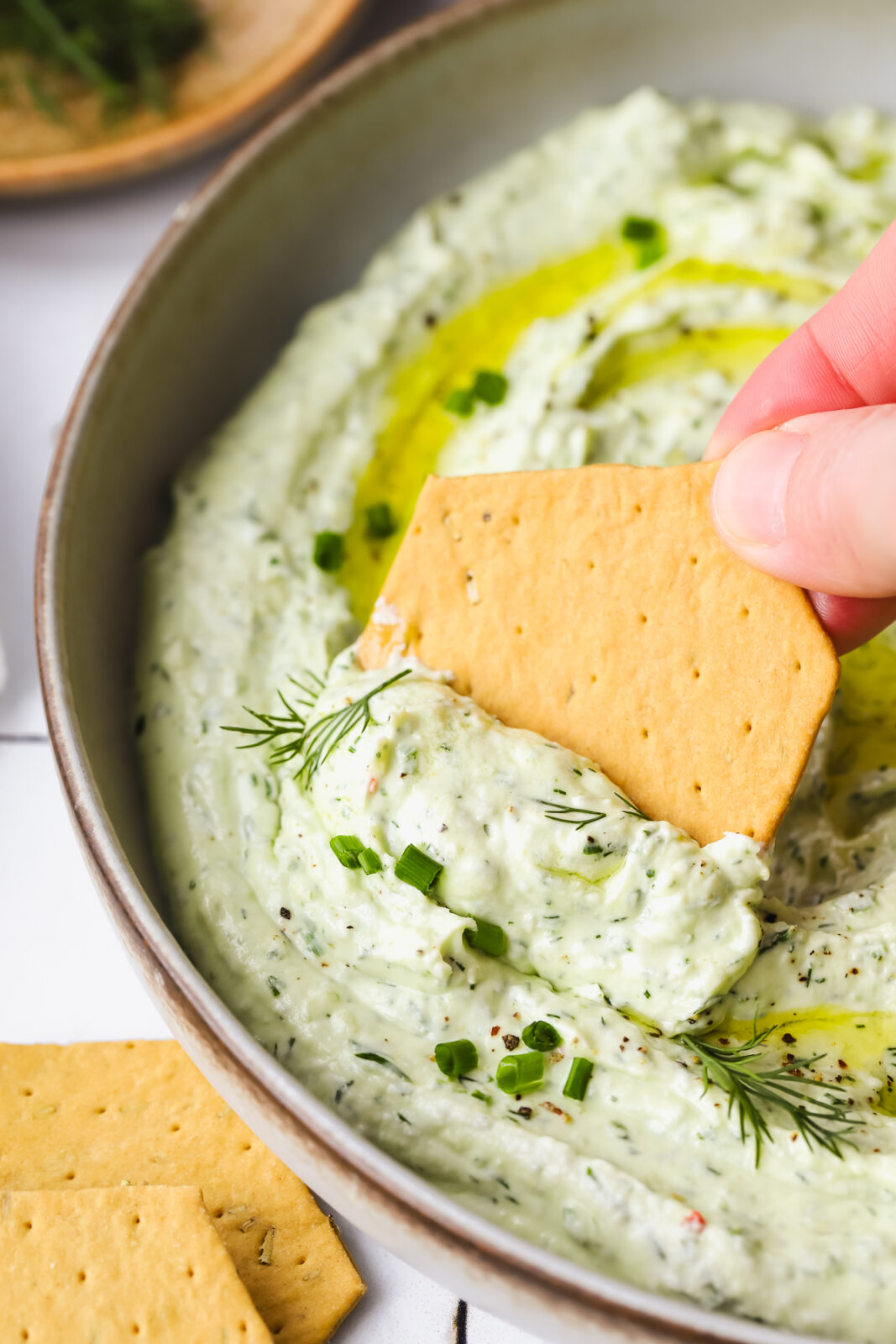cracker dipping into a goat cheese spread recipe