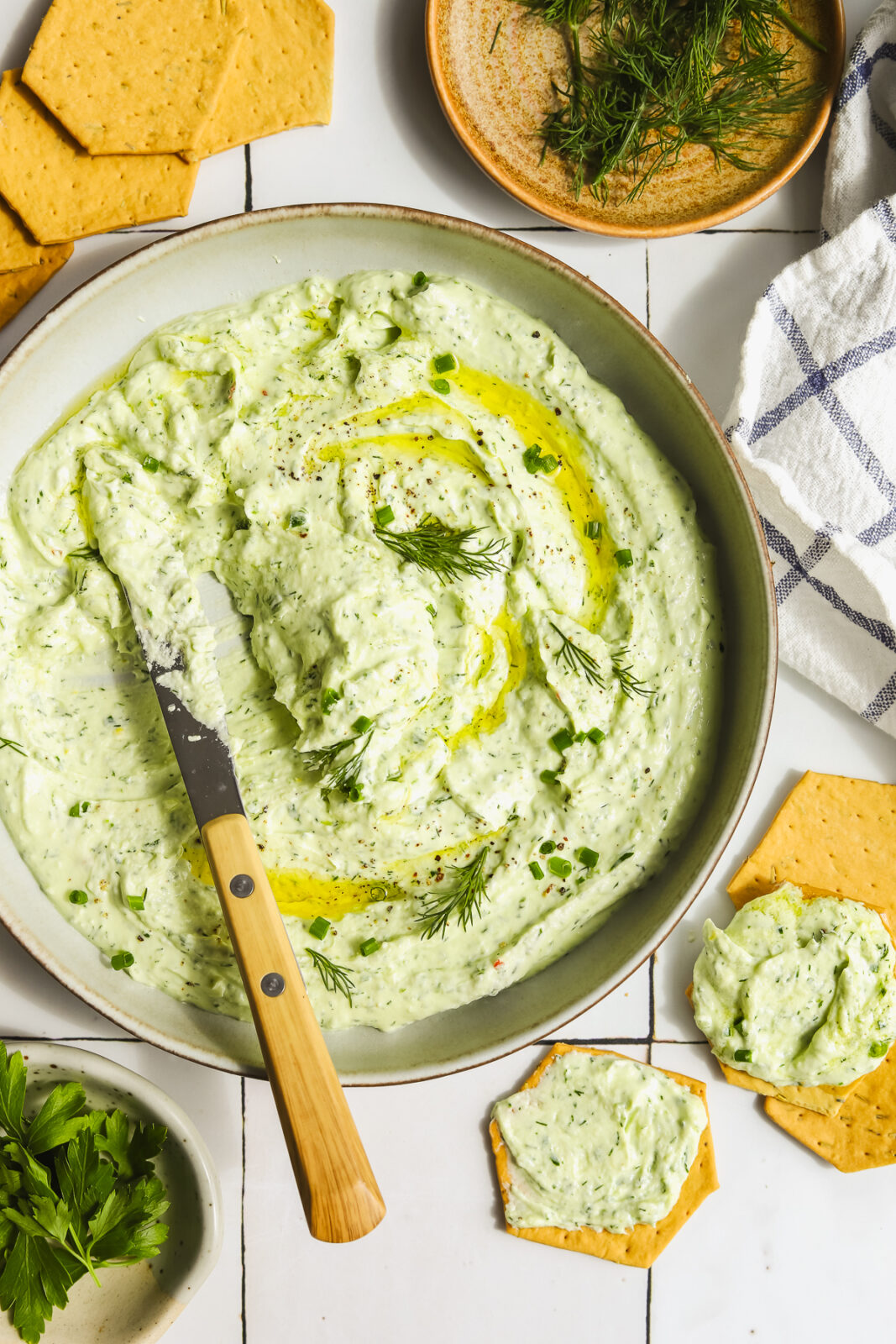 knife scooping out goat cheese dip with fresh herbs