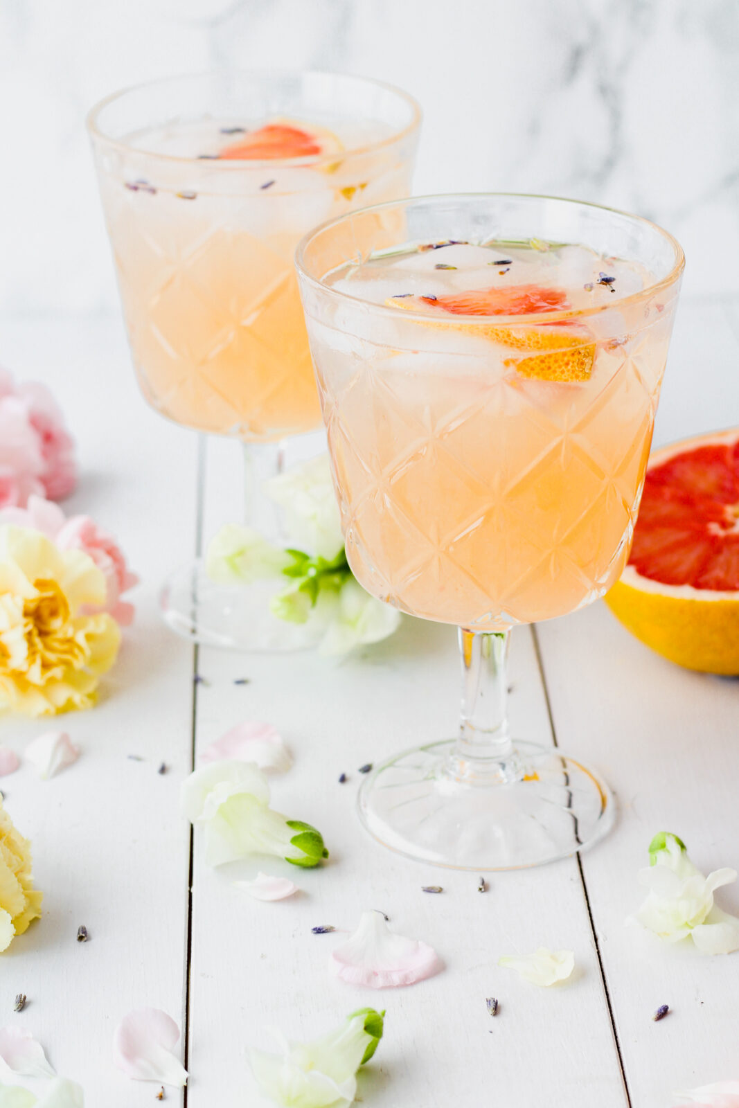 two cocktail glasses with grapefruit juice, lavender bitters and gin