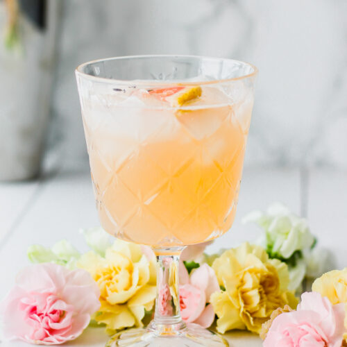 cocktail glass with grapefruit juice, lavender bitters and gin and florals