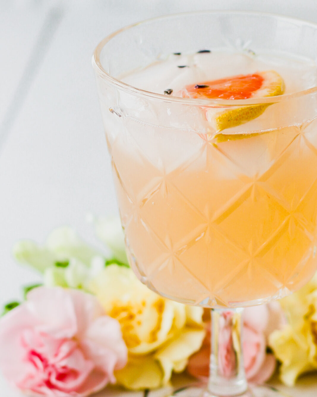 close up of a cocktail glass with a grapefruit gin cocktail and slice of grapefruit